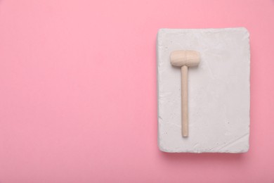 Educational toy for motor skills development. Excavation kit (plaster and wooden mallet) on pink background, top view with space for text