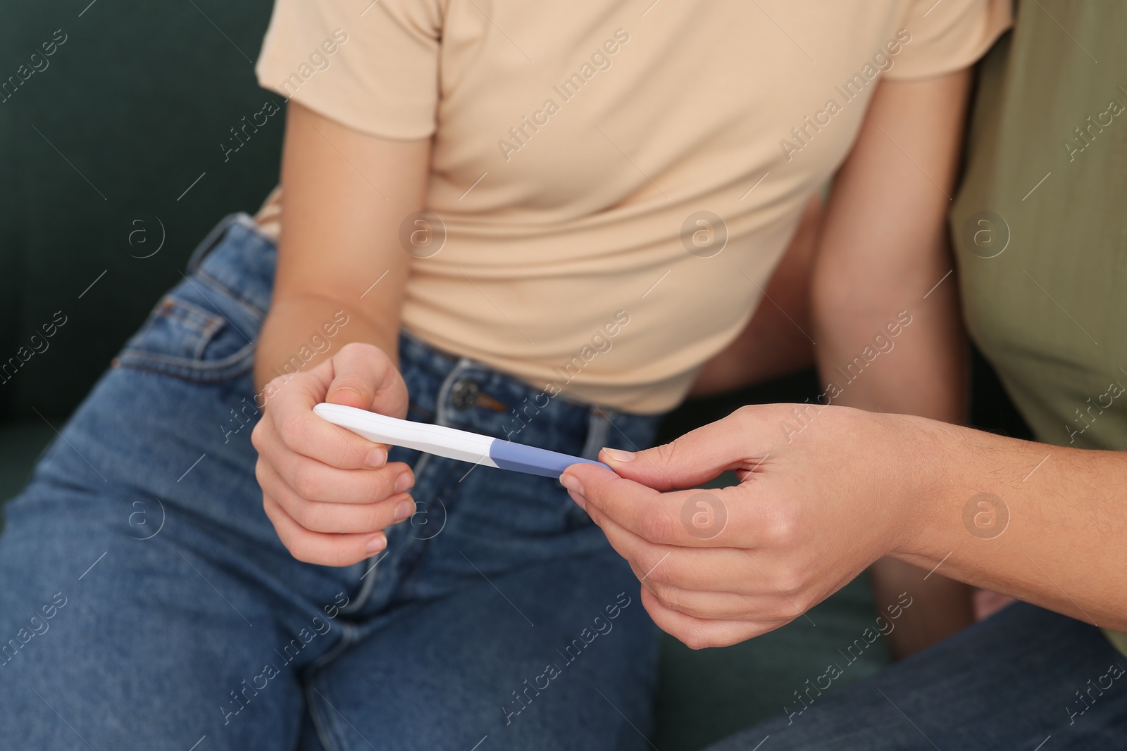 Photo of Young woman showing her mother pregnancy test, closeup. Grandparent reaction to future grandson