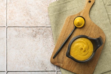 Tasty mustard sauce on light tiled table, top view. Space for text