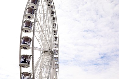 Beautiful Ferris wheel against cloudy sky, low angle view. Space for text