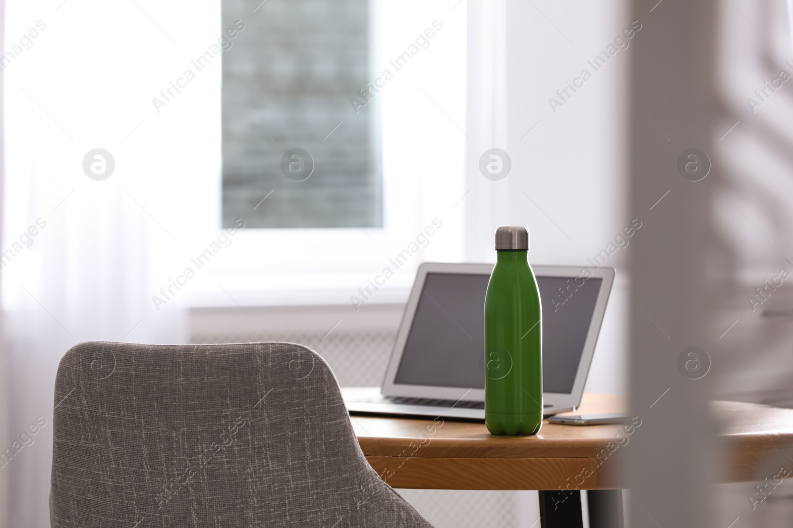 Photo of Thermo bottle on table in modern office