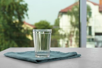 Photo of Glass of pure water on white table near window, space for text