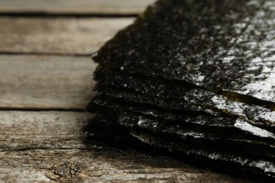 Stack of dry nori sheets on wooden table, closeup. Space for text