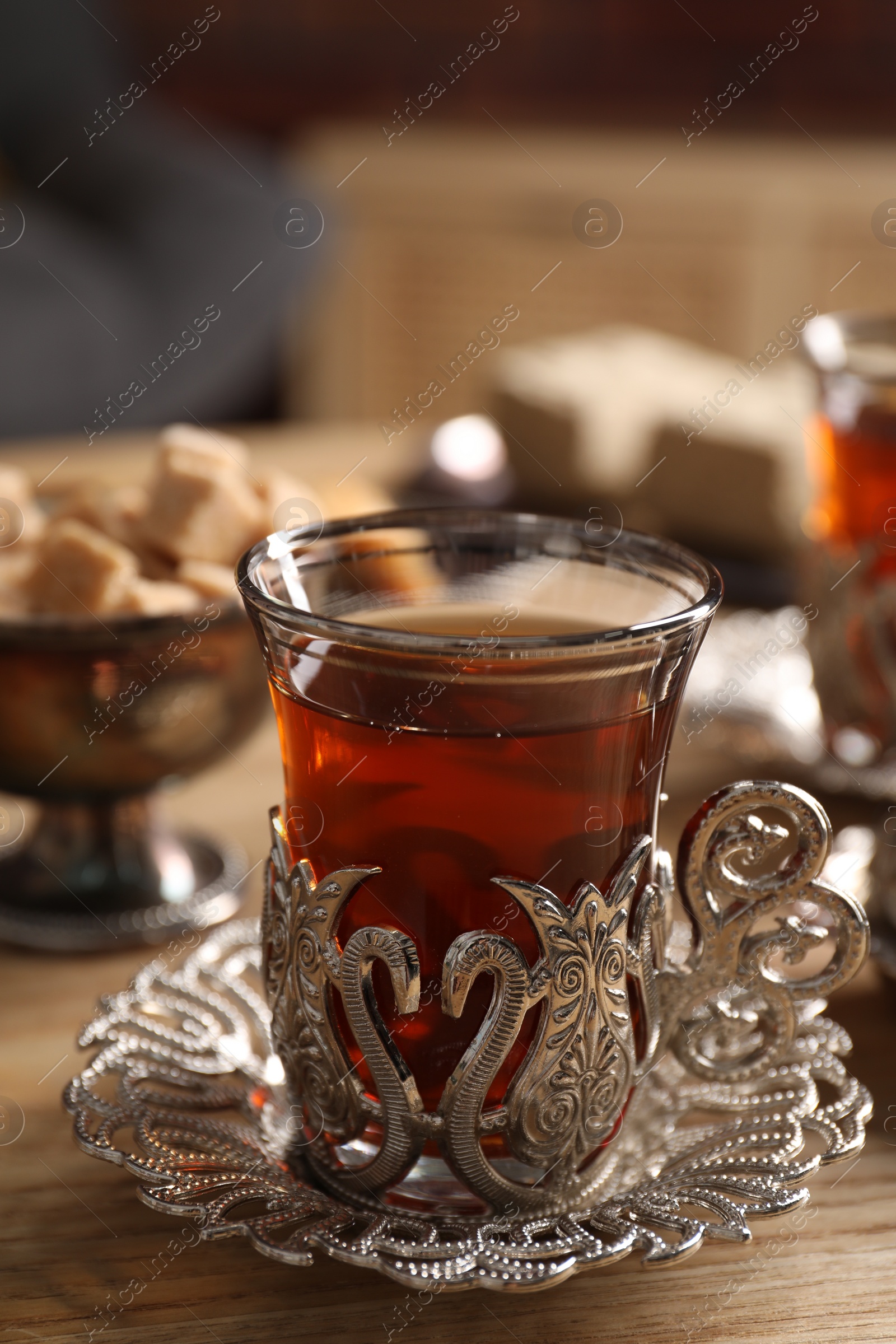 Photo of Glass of traditional Turkish tea in vintage holder on wooden table, closeup