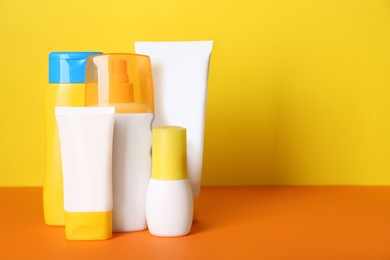 Different suntan products on color background. Space for text