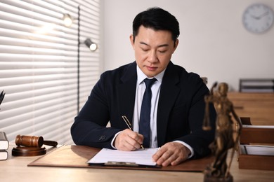 Notary writing notes at wooden table in office