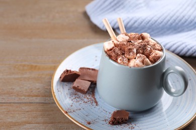 Photo of Cup of aromatic hot chocolate with marshmallows and cocoa powder served on table, closeup. Space for text