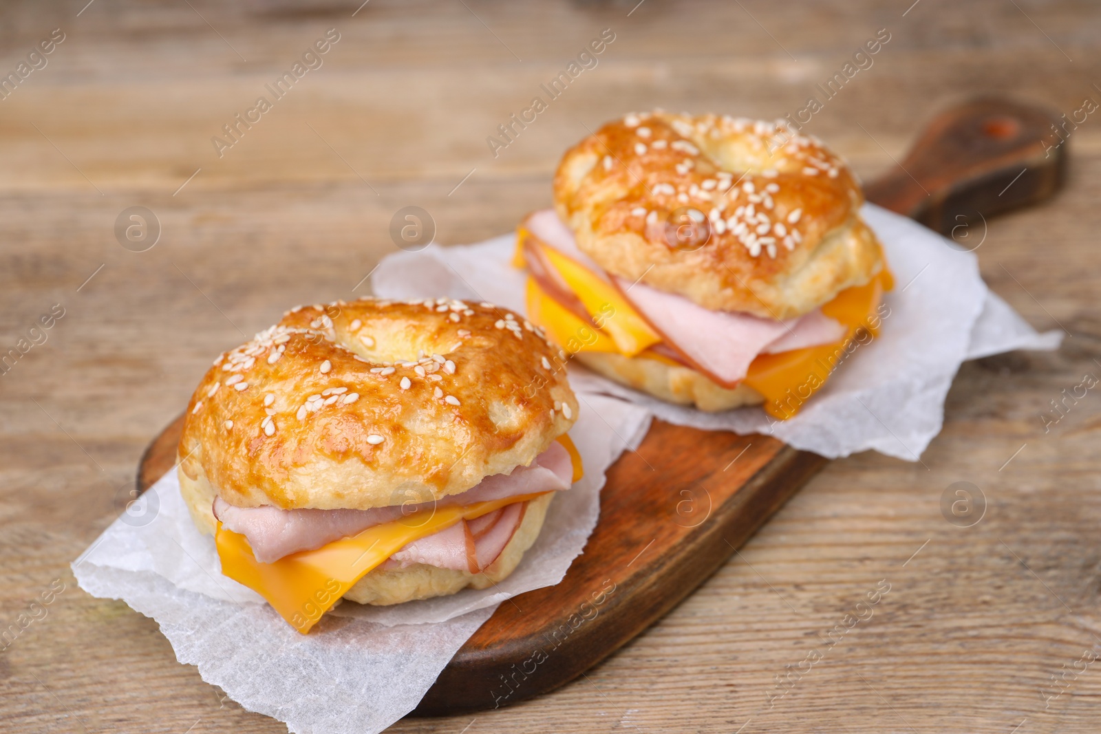 Delicious bagels with ham and cheese on wooden table Photo of Delicious bagels with ham and cheese on wooden table