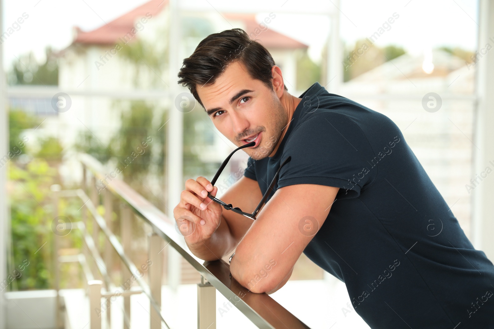 Photo of Portrait of handsome young man leaning on railing indoors