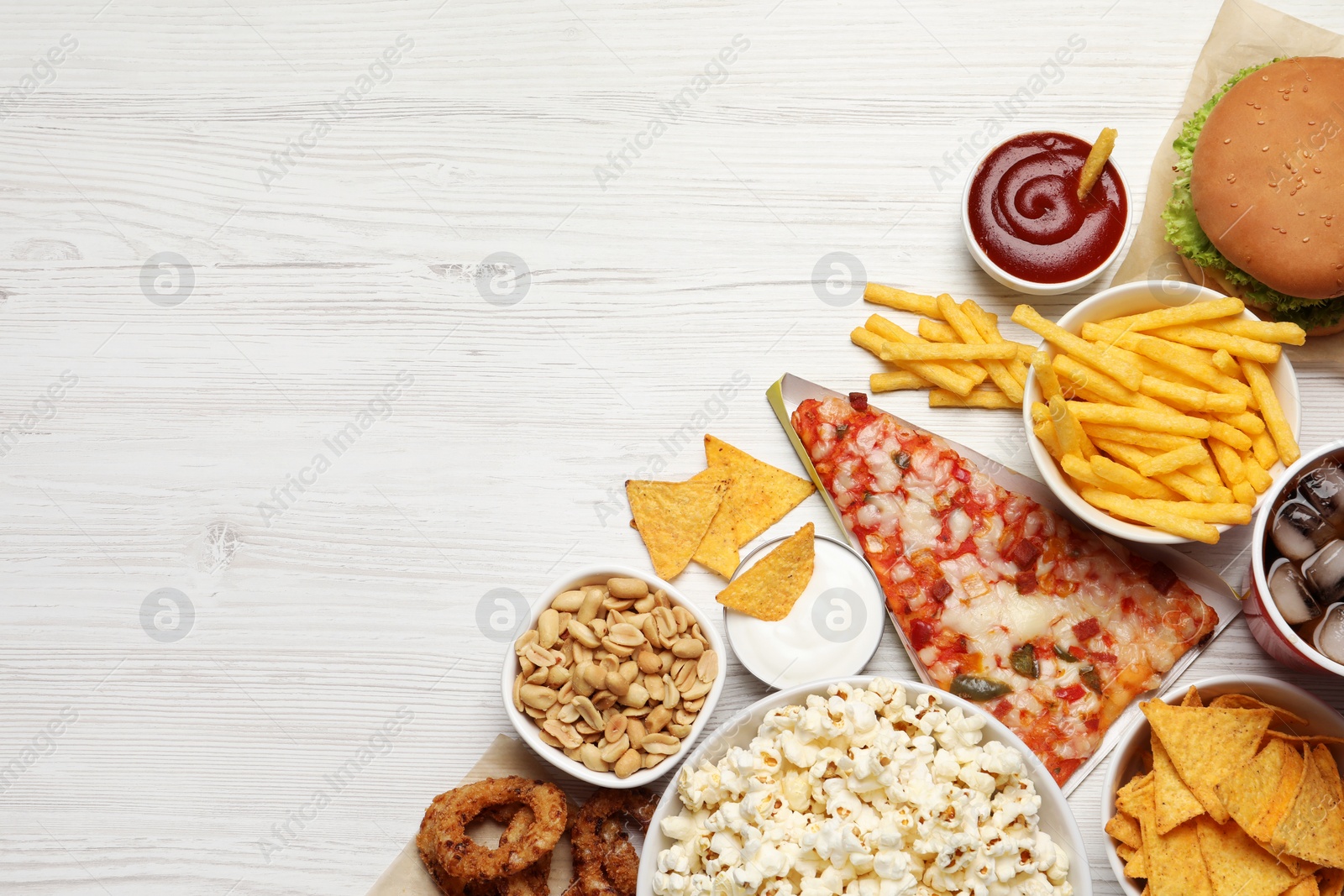 Photo of French fries, pizza and other fast food on white wooden table, flat lay with space for text