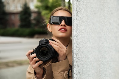 Private detective with modern camera spying on city street