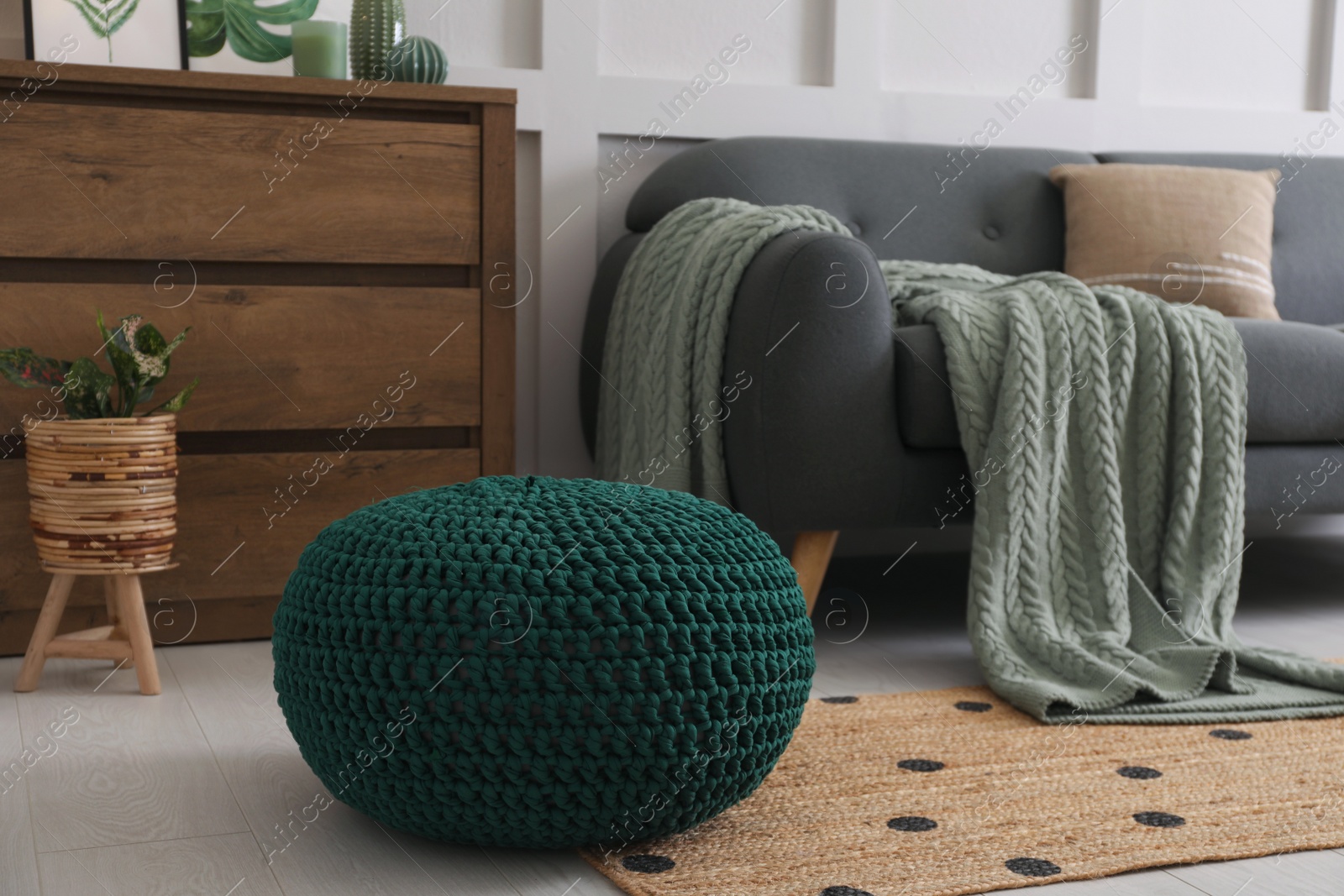 Photo of Knitted pouf near sofa in living room