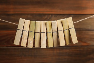 Many clothespins on rope against wooden background