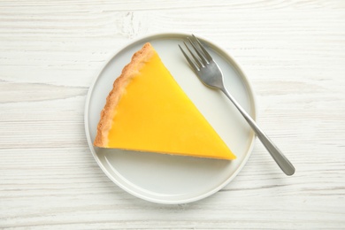 Photo of Slice of delicious homemade lemon pie on white wooden table, top view