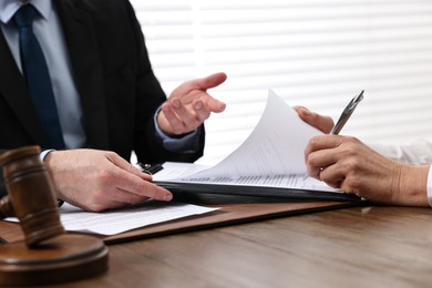 Senior woman signing document in lawyer's office, closeup