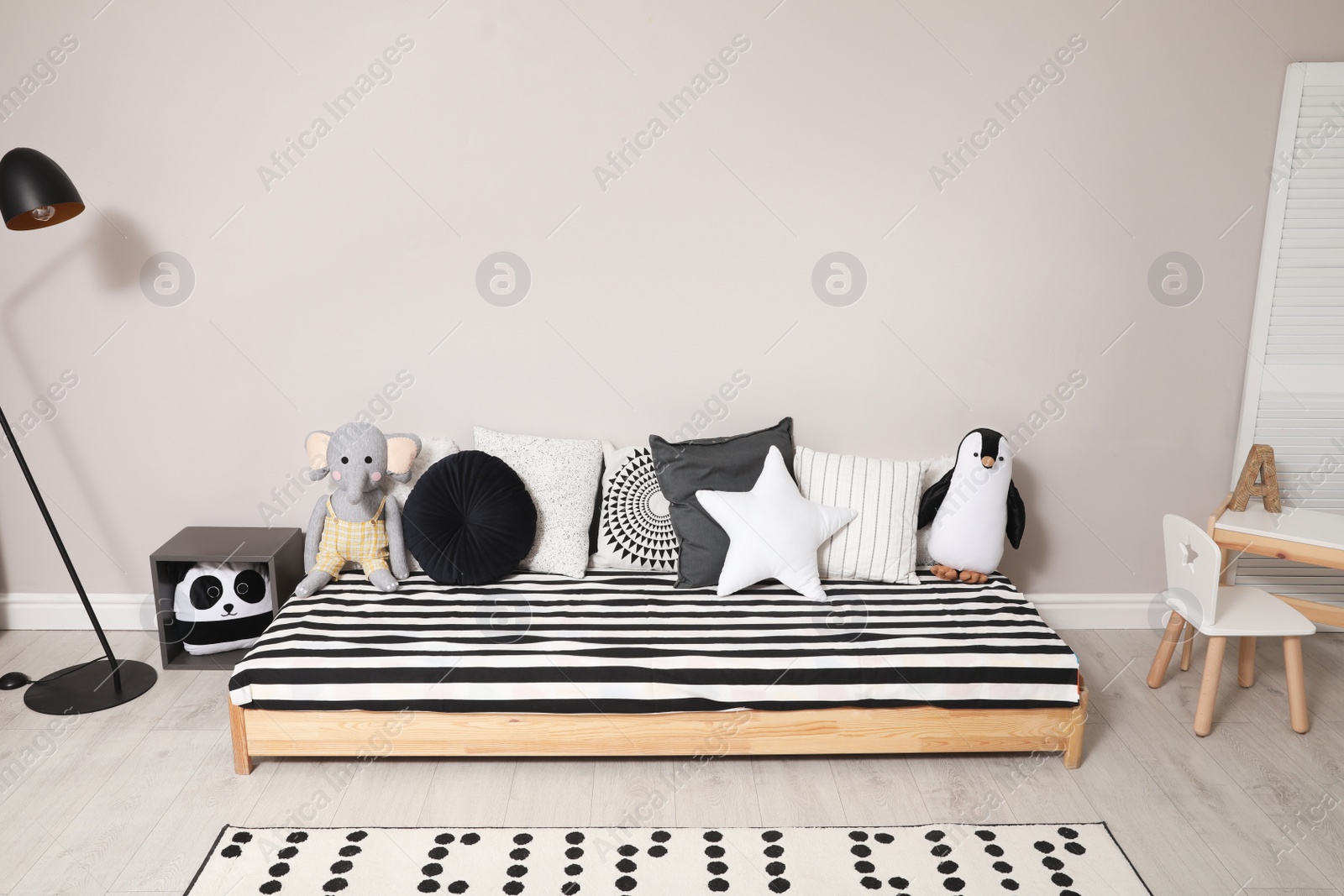 Photo of Cute kids room with stylish comfortable floor bed and toys. Montessori interior