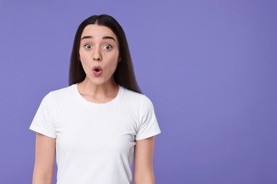 Portrait of surprised woman on violet background. Space for text