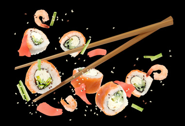 Delicious sushi rolls and ingredients on black background