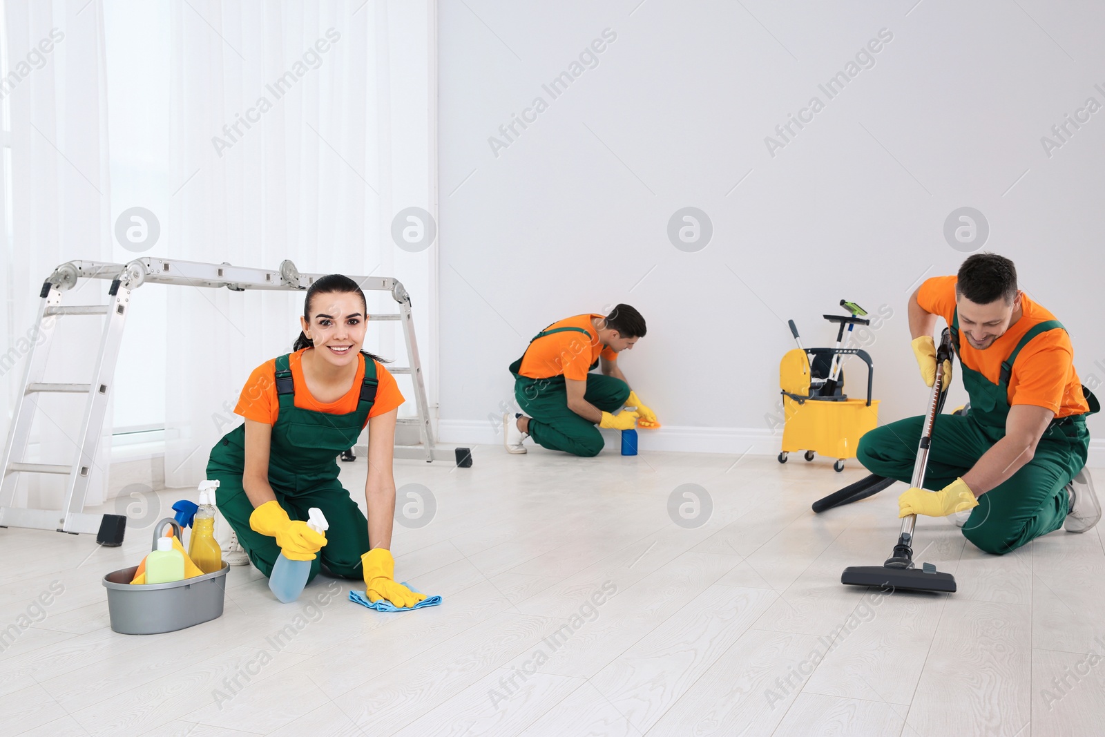 Photo of Team of professional janitors cleaning room after renovation