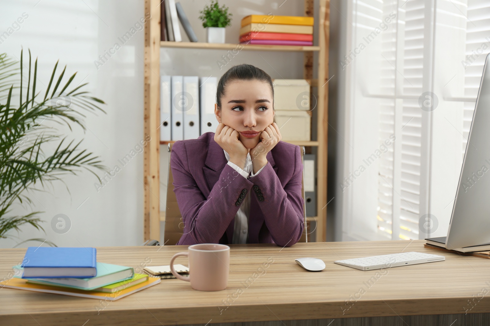 Photo of Lazy employee wasting time at table in office