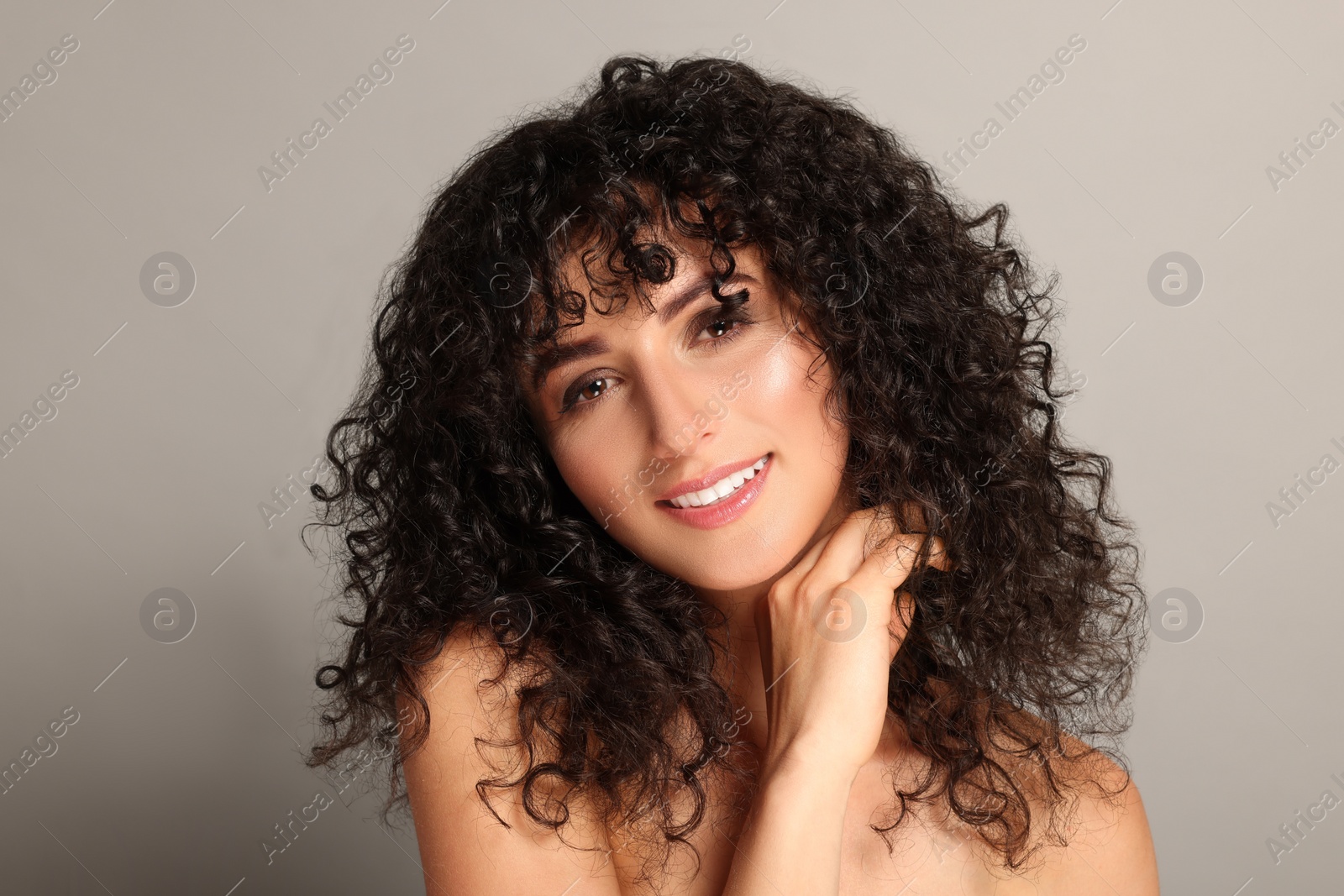 Photo of Beautiful young woman with long curly hair on light grey background