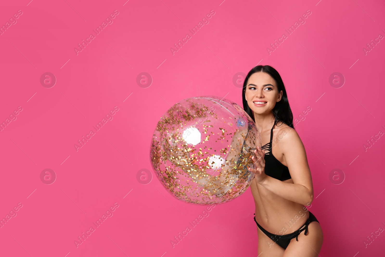 Photo of Beautiful young woman in stylish bikini with beach ball on pink background. Space for text