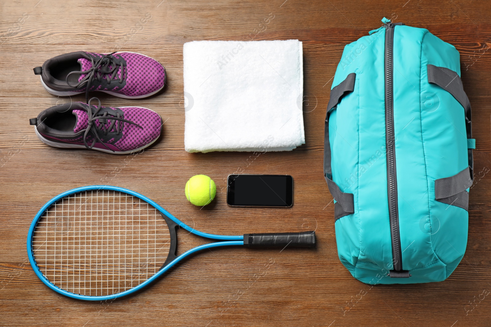 Photo of Flat lay composition with sports bag and equipment for tennis on wooden floor, top view