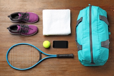 Flat lay composition with sports bag and equipment for tennis on wooden floor, top view