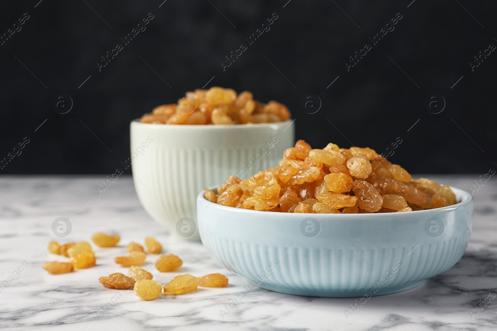 Photo of Bowls with raisins on marble table. Dried fruit as healthy snack