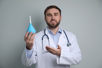 Photo of Doctor holding rubber enema on grey background