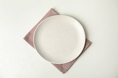 Photo of Empty plate and napkin on white table, top view