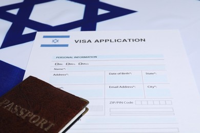 Photo of Immigration to Israel. Visa application form and passport on flag, closeup
