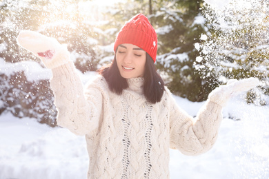 Photo of Happy young woman playing with snow outdoors. Winter vacation