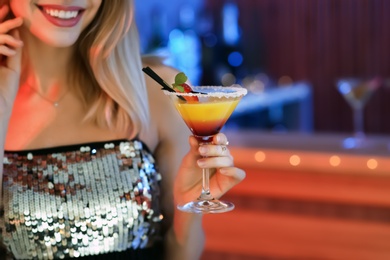 Photo of Young woman with glass of martini cocktail in bar, closeup. Space for text