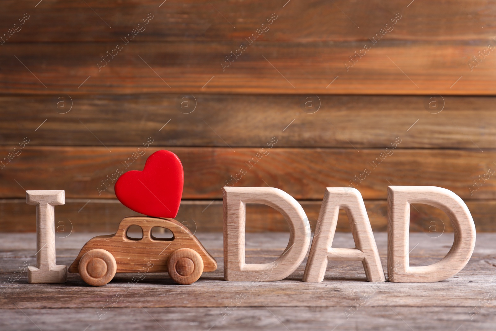 Photo of Phrase I LOVE DAD and toy car on table. Father's day celebration