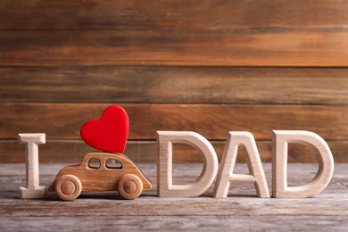 Photo of Phrase I LOVE DAD and toy car on table. Father's day celebration