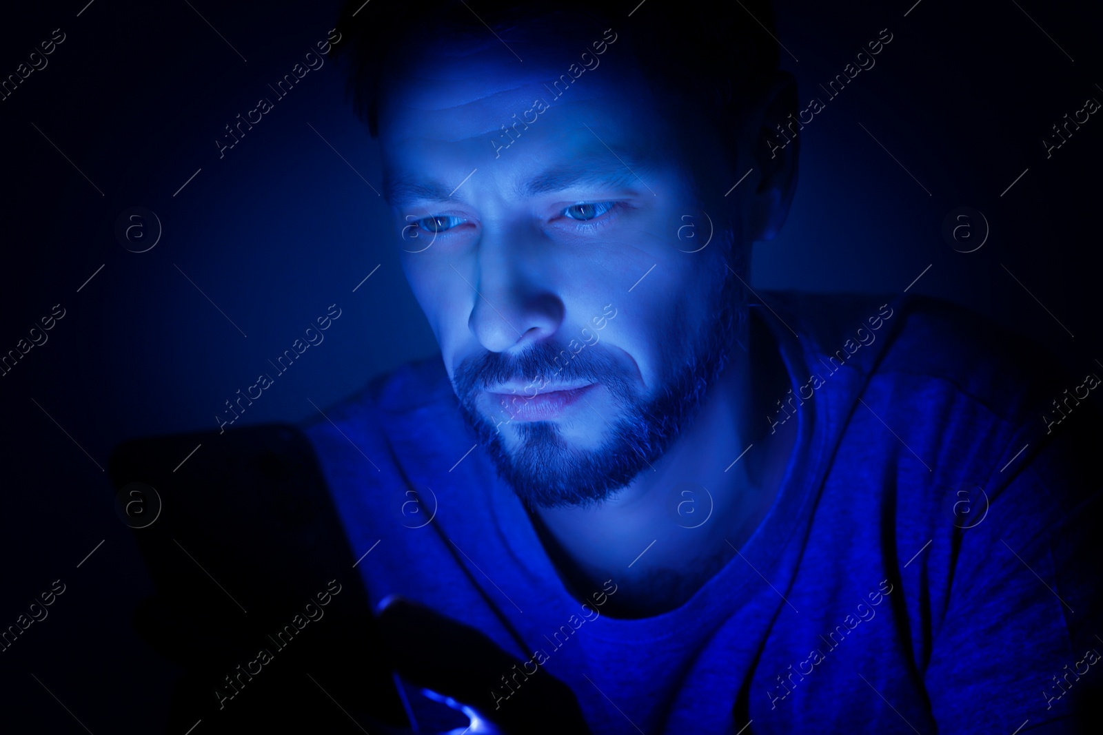 Image of Internet addiction. Man using smartphone at night. Toned in blue