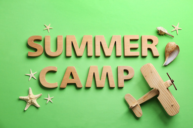 Flat lay composition with phrase SUMMER CAMP made of wooden letters on green background
