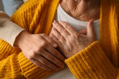 Photo of Young and elderly women hugging, closeup view