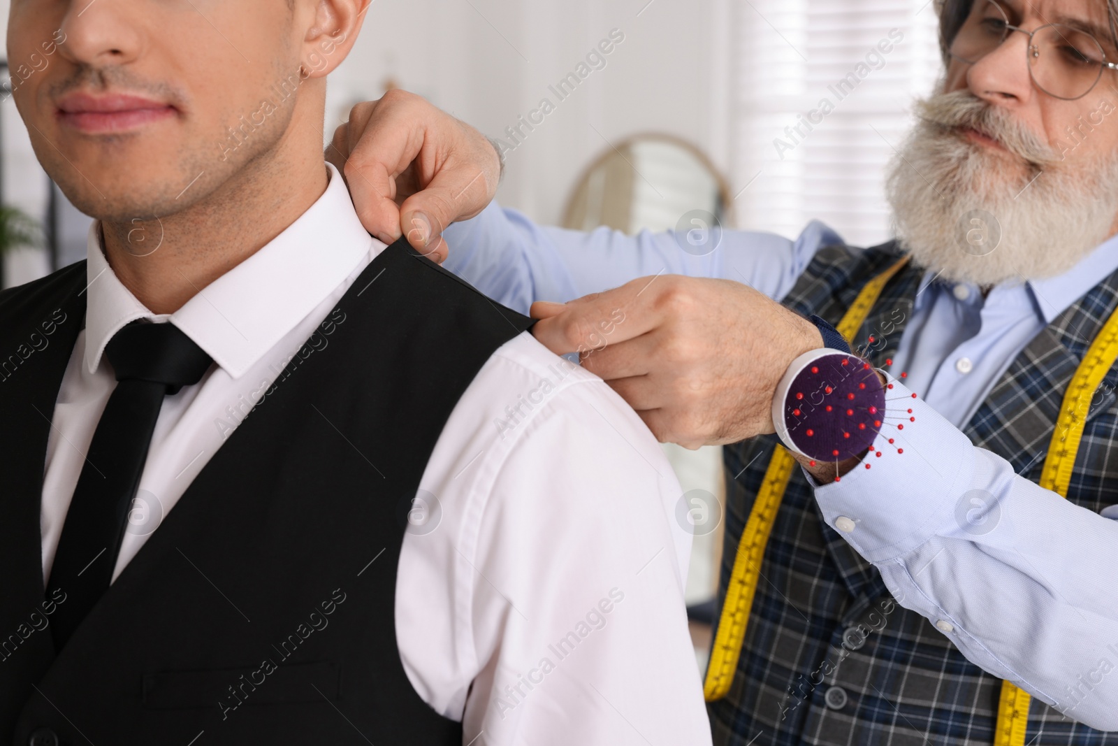 Photo of Professional tailor working with client in atelier, closeup