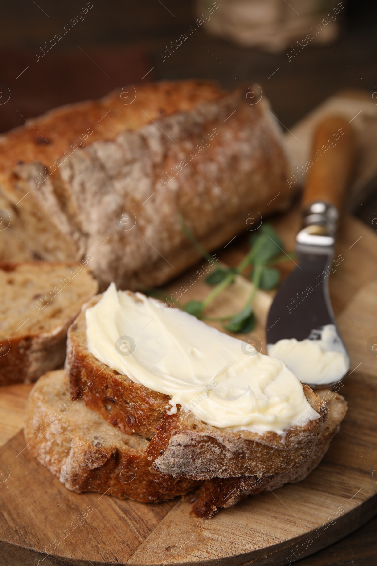 Photo of Slices of tasty bread with butter and knife on wooden board, closeup, Space for text
