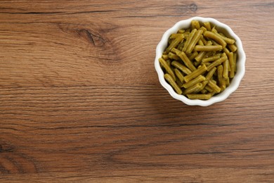 Photo of Canned green beans on wooden table, top view. Space for text