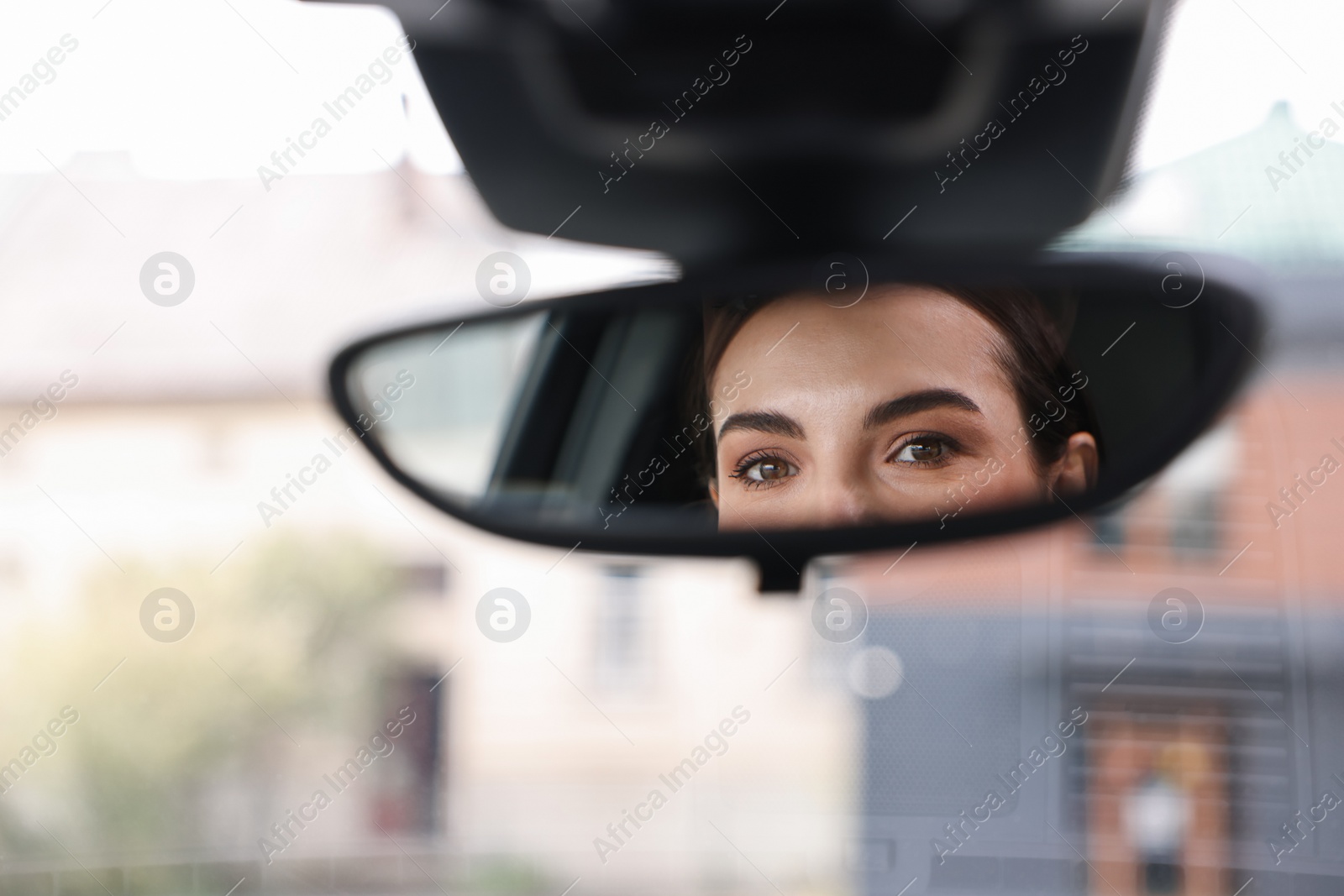 Photo of Woman driving her car, reflection in rear view mirror