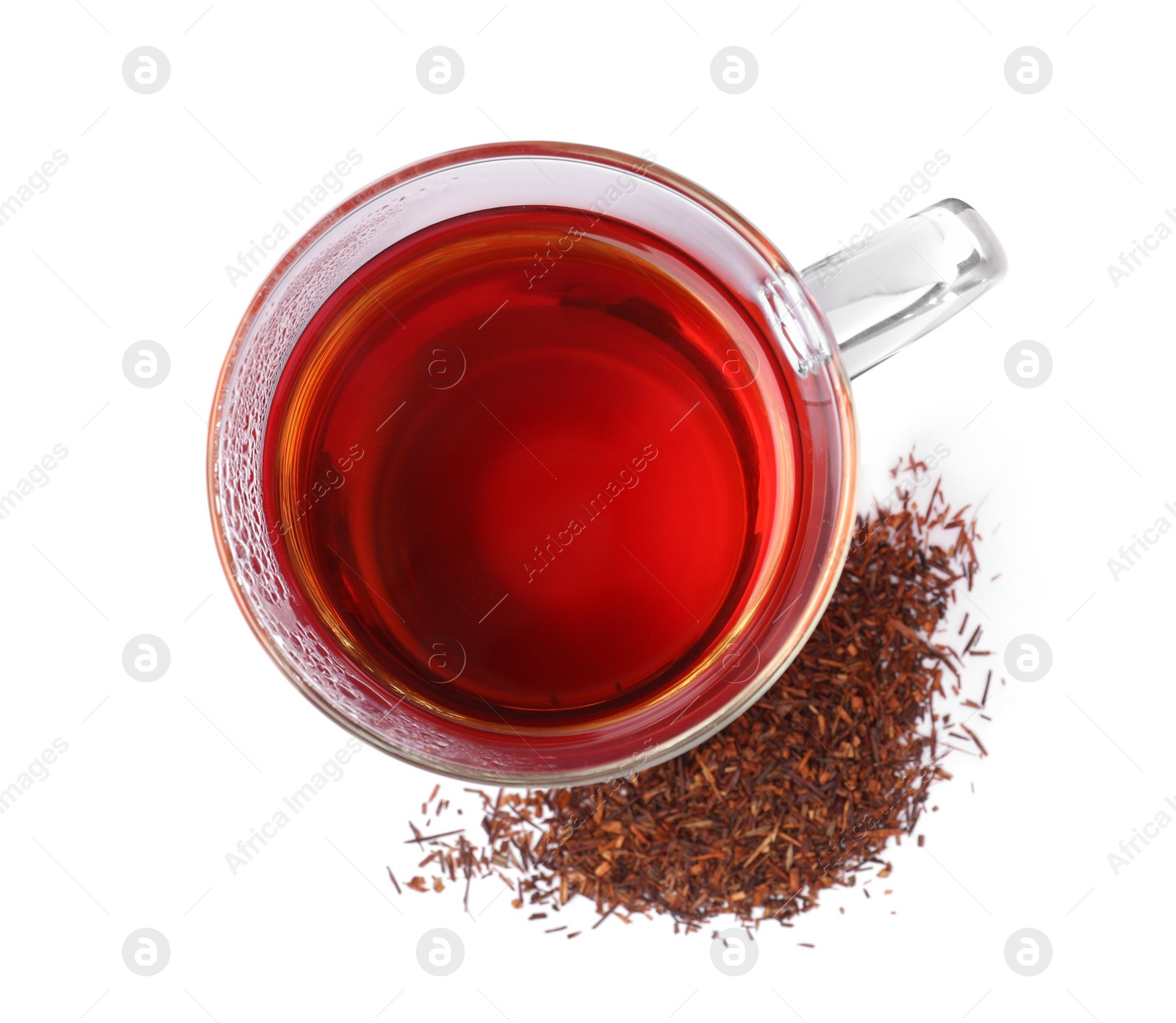 Photo of Aromatic rooibos tea in glass cup and scattered dry leaves on white background, top view