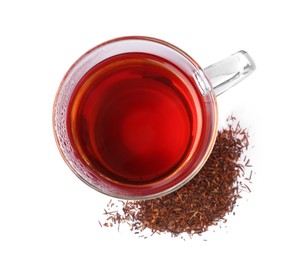 Photo of Aromatic rooibos tea in glass cup and scattered dry leaves on white background, top view