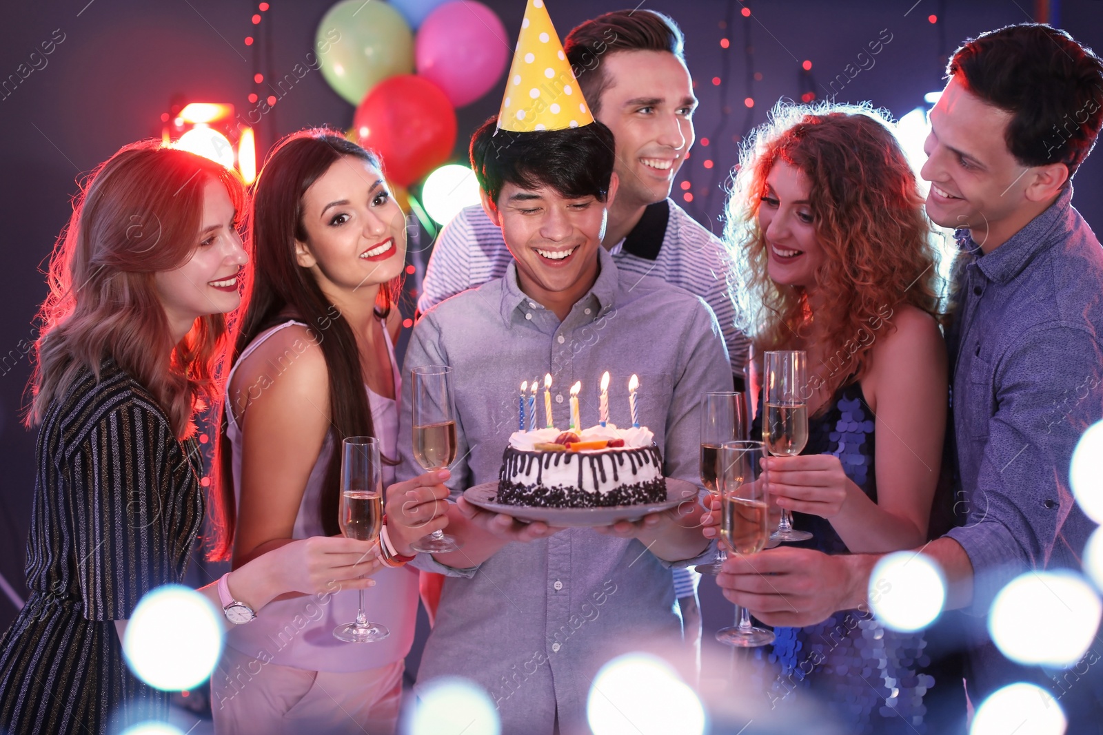 Photo of Young people celebrating birthday with cake in nightclub