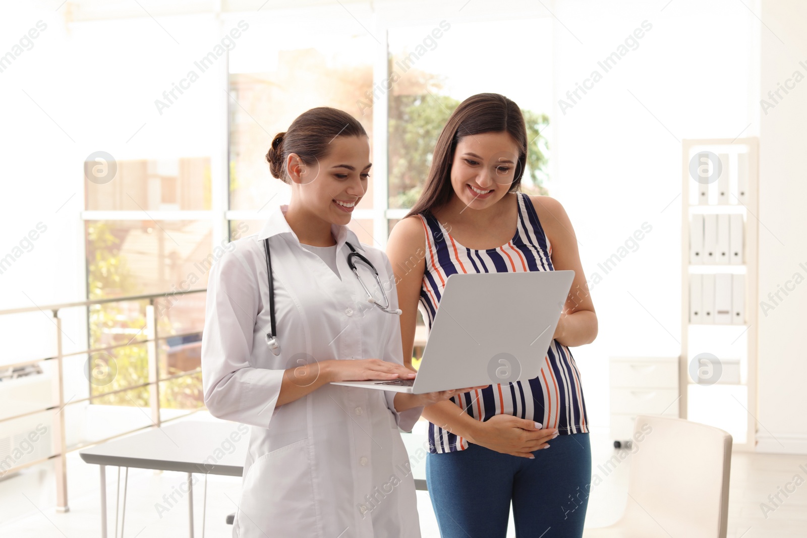 Photo of Young doctor with pregnant woman in hospital. Patient consultation