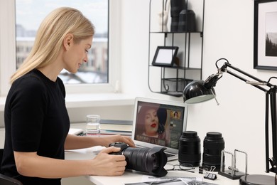 Photo of Professional photographer with digital camera at table in office