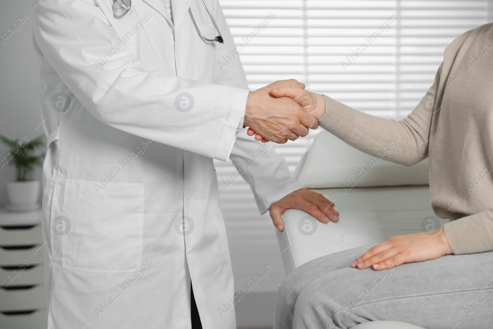 Photo of Senior doctor shaking hands with patient in clinic, closeup