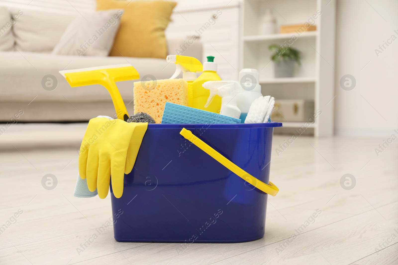 Photo of Different cleaning supplies in bucket on floor at home